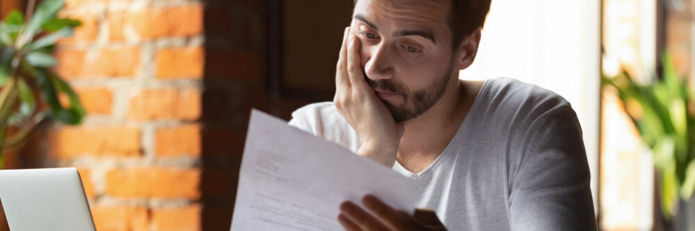 Confused,Frustrated,Young,Man,Reading,Letter,In,Cafe,,Debt,Notification,